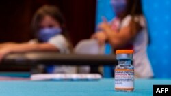 Un flacon de la nouvelle dose pour enfants du vaccin Pfizer-BioNTech Covid-19 se trouve au premier plan alors que des enfants jouent dans une chambre d'hôpital en attendant de pouvoir recevoir le vaccin à l'hôpital Hartford de Hartford, Connecticut, le 2 novembre 2021.