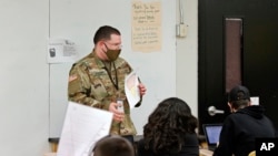 Substitute teacher and New Mexico Army National Guard specialist Michael Stockwell substitute holds up a geology assignment while teaching students at Alamogordo High School.