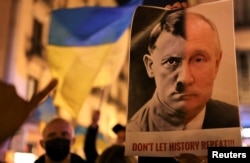 Seseorang memegang spanduk dengan wajah gabungan antara Vladimir Putin dan diktator Nazi Adolf Hitler selama protes anti-perang, setelah Presiden Rusia Vladimir Putin mengizinkan operasi militer besar-besaran melawan Ukraina, di Barcelona, Spanyol, 24 Februari 2022. (Foto: REUTERS/Nacho Doce)