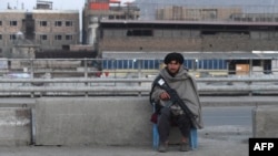 A Taliban fighter sits while guarding a road in Kabul, Feb. 20, 2022.