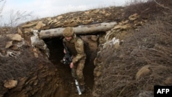 Seorang prajurit Ukraina berjalan di sepanjang parit pada posisi di garis depan dengan separatis yang didukung Rusia di dekat pemukiman Troitske di wilayah Lugansk pada 22 Februari 2022. (Foto: AFP)