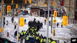 Police gather near the site of a trucker blockade in Ottawa, Feb. 18, 2022. Police began arresting protesters and towing away trucks Friday in a bid to break the three-week siege of Canada's capital by hundreds of truckers angry about the country's COVID-19 restrictions.