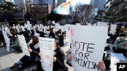 People hold signs at a rally supporting feminism in Seoul, South Korea, Feb. 12, 2022.