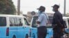 Agentes da polícia monitoram o fluxo de passageiros para os taxis, em Luanda.