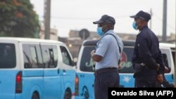 Agentes da polícia monitoram o fluxo de passageiros para os taxis, em Luanda.