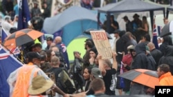 FILE - Protesters stand in the rain in Parliament grounds in Wellington on Feb. 12, 2022, on the fifth day of demonstrations against Covid restrictions. 