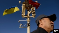 资料照：一名男子走过北京天安门广场灯柱上悬挂的中国与乌克兰国旗。（2013年12月5日）