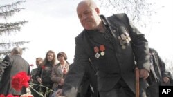 A veteran "liquidator" at the Chernobyl nuclear reactor places flowers during a ceremony to honor victims of the Chernobyl disaster, in Krasnoyarsk, April 26, 2011