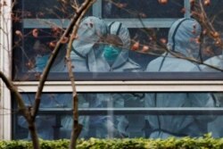 Members of the World Health Organization team, tasked with investigating the origins of the coronavirus disease, don personal protection suits during a visit at the Hubei Animal Epidemic Disease Prevention and Control Center in Wuhan, Feb. 2, 2021.