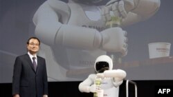 Pemimpin perusahaan Honda Motor Co. Takanobu Ito berdiri di dekat robot "Asimo" saat menggelar konferensi pers dalam Tokyo Motor Show, Jepang tahun 2011 (Foto: dok). Takanobu Ito, akan mundur dari posisinya sebagai direktur perusahaan tersebut, menyusul kemelut skandal kantong udara mobil yang buruk, Senin (23/2).