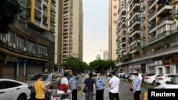 Police officers speak to people behind a police line near a residential area 