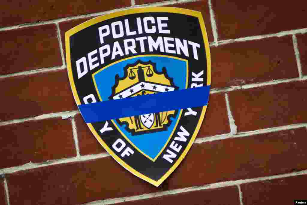 Logo NYPD di tempat peringatan dadakan yang didirikan di lokasi tempat dua polisi ditembak di kepalanya di Brooklyn, New York, 22 Desember 2014.