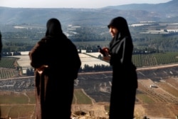 Lebanese villager women check their fields that were burned Sunday by Israeli army shells, in the southern Lebanese border village of Maroun el-Ras, Lebanon, Sept. 2, 2019.