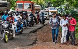 Commuters wearing masks wait at a traffic intersection in Kochi, Kerala state, India, Sept.28, 2020.