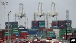 រថយន្ត​ដឹក​ទំនិញ​តជួរ​នៅ​កំពង់​ផែ​ក្រុង​ Long Beach រដ្ឋ California។ កម្មករ​និង​ប្រតិបត្តិករ​នៅកំពង់ផែសហរដ្ឋ​អាមេរិក​បាន​សម្រេច​កិច្ច​ព្រម​ព្រៀង​បណ្តោះអាសន្ន​មួយ​លើ​កិច្ច​សន្យា​ការងារ​ថ្មី​។