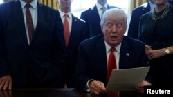 도널드 트럼프 미국 대통령이 24일 백악관 집무실에서 미국 주요 기업 중역들이 지켜보는 가운데 규제개혁 행정명령에 서명했다.