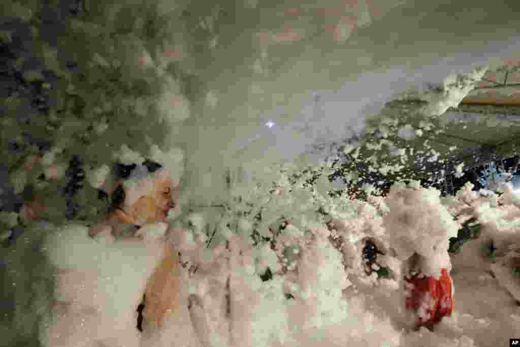 People enjoy a foam party in a disco, in the Tuscany region sea resort of Castiglione della Pescaiadella Pescaia, Italy. 