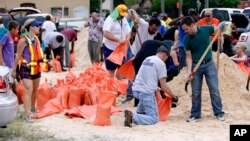 کارکنان شهرداری و داوطلبان کیسه های شن را برای حفاظت خانه ها آماده می کنند.