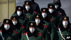 FILE - Paramilitary policemen wear face masks as they march in formation into a pedestrian underpass next to Tiananmen Square in Beijing, Feb. 4, 2020. 