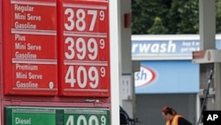 Prices are shown as Jaqueline Henderson pumps gas at a station in Portland, Ore., Friday, July 29, 2011