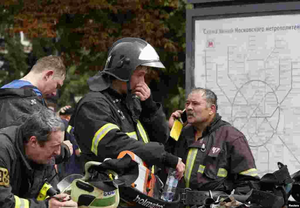 Para anggota layanan darurat dekat peta kereta bawah tanah di luar stasiun di Moskow (15/7). (Reuters/Sergei Karpukhin)