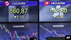 A currency trader walks by screens showing the foreign exchange rates at the foreign exchange dealing room in Seoul, South Korea, Dec. 24, 2020.