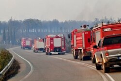 A convoy of firetrucks use a road during a wildfire in Lalas village, near Olympia town, western Greece, Aug. 5, 2021.