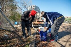 Ben Mitchell and Deon Sanders work at a public water distribution site after a recent bout of cold weather caused large numbers of water outages, in Jackson, Mississippi, March 4, 2021.