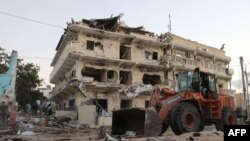 FILE - A backhoe loader clean the street outside the Maka Al-Mukarama hotel in the Somalia capital, Mogadishu on March 1, 2019 after a car bomb exploded, killing at least five people and wounding 25 others. 
