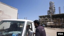 Pekerja Libya berbicara di dekat fasilitas penyulingan minyak Zawiya, dekat Tripoli. Uni Eropa akan menghapuskan sanksi minyak atas Libya, sehingga perusahaan minyak Libya akan bisa kembali beroperasi.