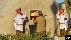 Cuba's President Raul Castro places the ashes of his older brother Fidel Castro into a niche in his tomb, a simple, grey, round stone about 15 feet high at the Santa Ifigenia cemetery in Santiago, Dec.4, 2016. 