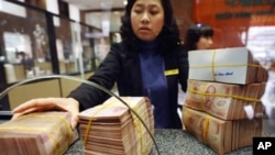 A local commercial bank staff receives bricks of dong bank notes from a customer in Hanoi, February 23, 2011