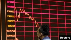 FILE - An investor looks at an electronic board showing stock information a brokerage house in Beijing, China, Aug. 26, 2015. 