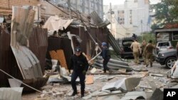 Seorang polisi dan petugas penyelamat berjalan di depan restoran RIA Pizza yang hancur akibat serangan Rusia di Kramatorsk, Ukraina, Selasa, 27 Juni 2023. (Foto: via AP)