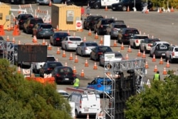FILE - People, in their cars, wait in line for coronavirus testing at Dodger Stadium in Los Angeles, California, July 14, 2020.