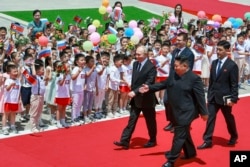 Presiden Rusia Vladimir Putin (kiri), dan pemimpin Korea Utara Kim Jong Un (latar depan kanan), menghadiri upacara penyambutan resmi di Lapangan Kim Il Sung di Pyongyang, Korea Utara, Rabu, 19 Juni 2024. (Vladimir Smirnov, Sputnik, Kremlin Foto Pool via AP)