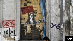 A man walks past a political graffiti in central Athens by artist Bleeps reading' Bid! a few items left on sale', May 4, 2017, one day after Greece and its creditors closed a troubled chapter on fiscal reforms.