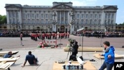 A TV crew works as members of the household brigade marching band walk in front of Buckingham palace, in London, on April 28, 2011.