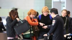 FILE - Travelers, left, and an official, right, argue at a security check at Hongqiao Airport's second terminal in Shanghai, China. 