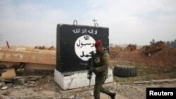 FILE - An Iraqi soldier walks next to a wall painted with the black flag commonly used by Islamic State militants, north of Mosul, Iraq, Jan. 21, 2017.