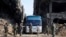 FILE - In this file photo released April 30, 2018 by the Syrian official news agency, SANA, Syrian government forces oversee a bus carrying al-Qaida-linked fighters during an evacuation from the Palestinian refugee camp of Yarmouk, near Damascus, Syria.