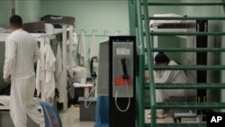  FILE - Public phones are seen near detainees in a residential pod during a media tour of the U.S. Immigration and Customs Enforcement detention center in Tacoma, Washington, Dec. 16, 2019. 