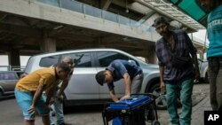 FILE - A vendor shows a power generator to customers at the Maracaibo flea marker, in Venezuela, May 23, 2019. 