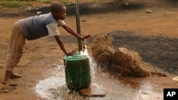 FILE - A child fills a container with water for domestic use in Delmas, east of Johannesburg, South Africa.