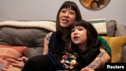 Stefany Stuber, 40, a Korean-American who speaks with her daughter Olivia Metzler, 7, about recent attacks on Asian Americans, watches TV with her daughter in Philadelphia, Pennsylvania, U.S., March 24, 2021. Picture taken March 24, 2021. REUTERS/Hannah B