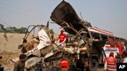 Para pekerja Pakistan memeriksa bus pegawai pemerintah yang hancur akibat ledakan bom di Peshawar, Pakistan (27/9). 