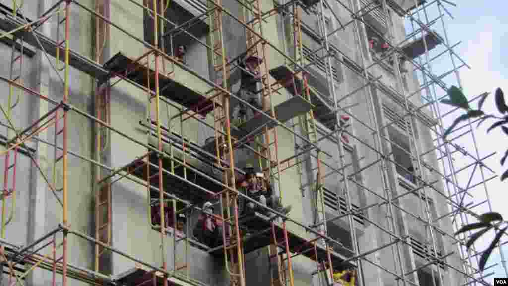 Construction workers on scaffolding ceased their work to watch opposition protest and take pictures, Phnom Penh, Oct. 23, 2013. (Khoun Theara/VOA Khmer)