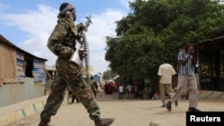 FILE - A Somali soldier patrols a street following a suicide car bomb and gun attack in Afgoye, Somalia, Oct. 19, 2016.