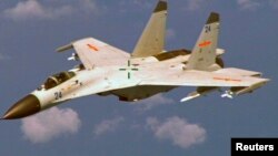 A Chinese J-11 fighter jet is seen flying near a U.S. Navy P-8 Poseidon about 215 km (135 miles) east of China's Hainan Island in this U.S. Department of Defense handout photo taken Aug. 19, 2014. 