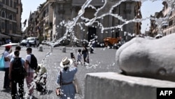 Orang-orang berjalan di Piazza del Popolo, Roma tengah saat gelombang panas melanda Italia, 17 Juli 2023.